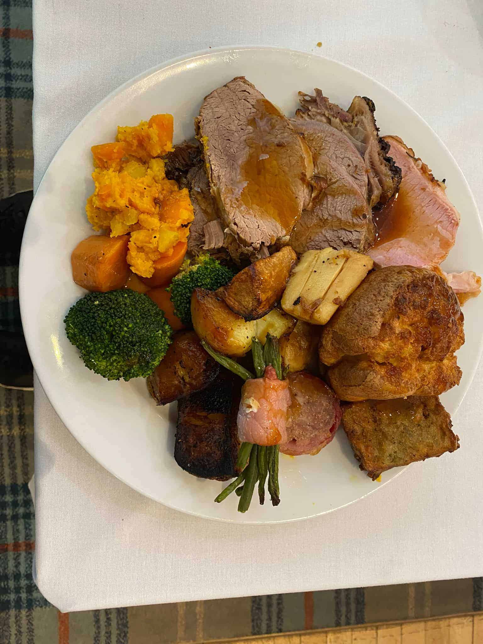 A plated Sunday roast at Horsforth Golf Club with sliced roast meat, roast potatoes, seasonal vegetables, a Yorkshire pudding, stuffing, and a pig in blanket.